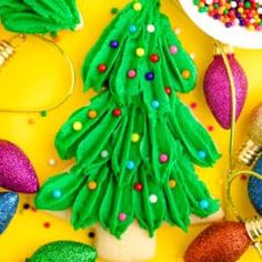 a christmas tree made out of green paper on top of a yellow surface with other holiday decorations