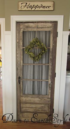 an old door with a wreath hanging on it's side and the words happiness written above it