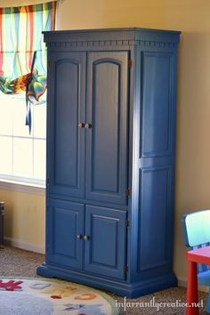 a blue armoire in a child's room with colorful furniture and curtains on the window sill