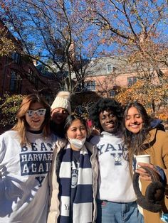 a group of people standing next to each other in front of trees with leaves on them