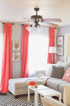 a living room with white furniture and orange curtains