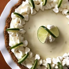 a white plate topped with a cheesecake covered in toppings and a lime slice