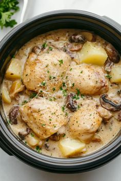 a crock pot filled with chicken, potatoes and mushrooms