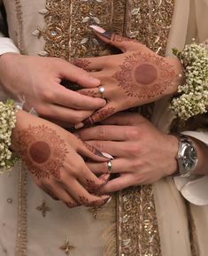 two brides holding hands with henna tattoos on their arms and the other hand