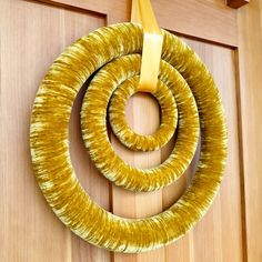 a wreath hanging on the front door with a yellow ribbon around it's loop