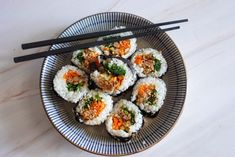 sushi is served on a plate with chopsticks and garnishes