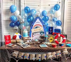 a table topped with lots of blue and white balloons in the shape of shark's teeth