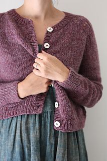 a woman is wearing a purple cardigan sweater