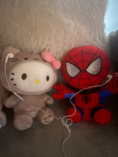 hello kitty and spiderman stuffed animals are on the floor next to eachother