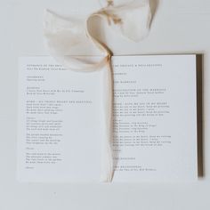 an open book with a ribbon on top of it next to a piece of paper