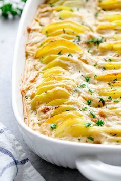 a casserole dish with potatoes and parsley in it on a white cloth