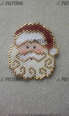 a beaded santa clause brooch with gold trimmings and red accents on it