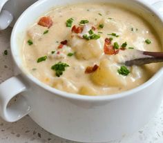 a white bowl filled with soup sitting on top of a table next to a spoon