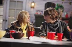 two people sitting at a table with red cups