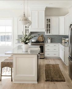 a kitchen with white cabinets and an island in the middle, along with stainless steel appliances