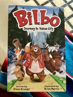 a children's book about bilbo is on the bed with other books