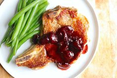 a white plate topped with meat covered in cranberry sauce next to green beans