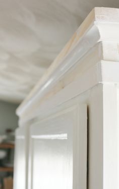 the corner of a white cabinet with molding on it's sides and bottom