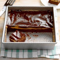 a pan filled with cake sitting on top of a table next to a knife and fork