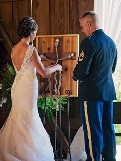 a bride and groom standing in front of a wooden cross during their wedding ceremony at the barn