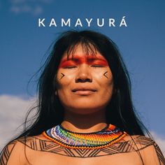 a native american woman with her face painted in red and black, standing against a blue sky