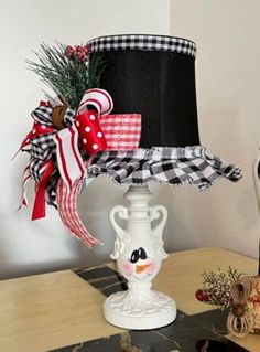 a lamp with a black and white hat on it sitting on a table next to a christmas tree