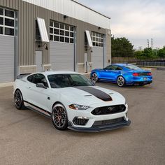 two ford mustangs parked in front of a building