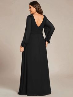 the back of a woman wearing a black dress with long sleeves and an open neckline