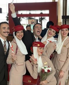 a group of people dressed in airline uniforms posing for the camera with their hands up