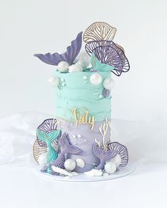 there is a cake decorated with sea shells and mermaid tail decorations on the top tier