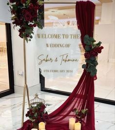 a welcome sign with flowers and candles in front of the entrance to a wedding venue