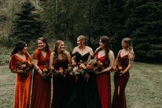 a group of women standing next to each other in front of some trees and grass