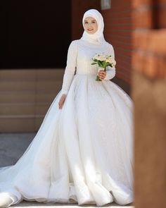 a woman in a white wedding dress is walking down the street wearing a hijab