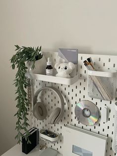 a white desk with various items on it and a plant in the corner next to it