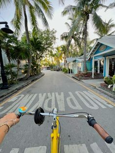 someone riding their bike down the street in front of some houses and palm tree's