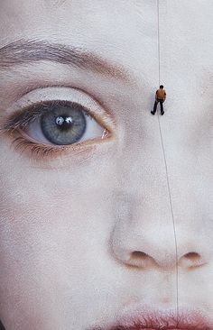 a man is tied to the side of a large poster with his face painted white