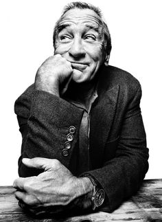 a black and white photo of a man sitting at a table with his hand on his chin