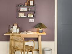 a wooden desk topped with a lamp next to a wall mounted book shelf filled with books