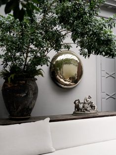 a white couch sitting under a mirror next to a potted plant