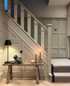 a wooden table sitting under a stair case next to a light on top of a lamp