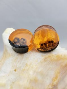 two yellow glass beads sitting on top of a shell