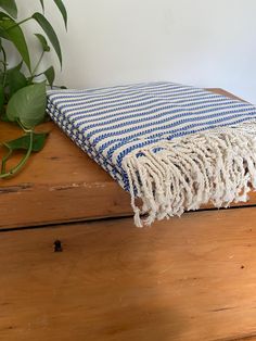 a blue and white blanket sitting on top of a wooden table next to a potted plant