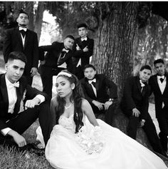 a group of young people dressed in formal wear sitting next to each other under a tree