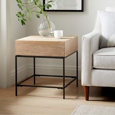 a living room with a couch, coffee table and vase on the end table in front of it