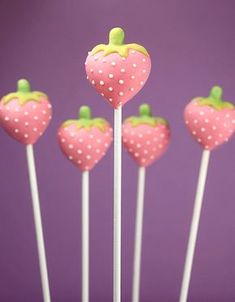 strawberry lollipops with polka dots on them sitting in front of a purple background