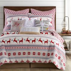 a bed with red and white christmas decorations on the comforter, pillows and pillow cases