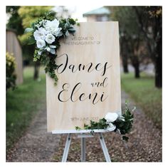 a wooden sign with flowers and greenery on it