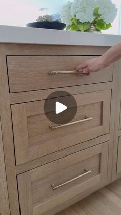 a person is opening the drawer on a kitchen counter top with flowers in the background