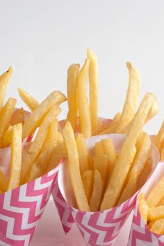 three paper cups filled with french fries on top of a table