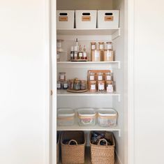 an organized pantry with white shelves and baskets